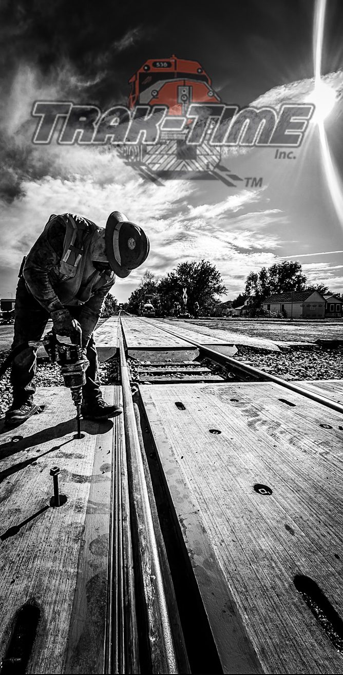 A man working on railroad tracks under a dramatic sky.