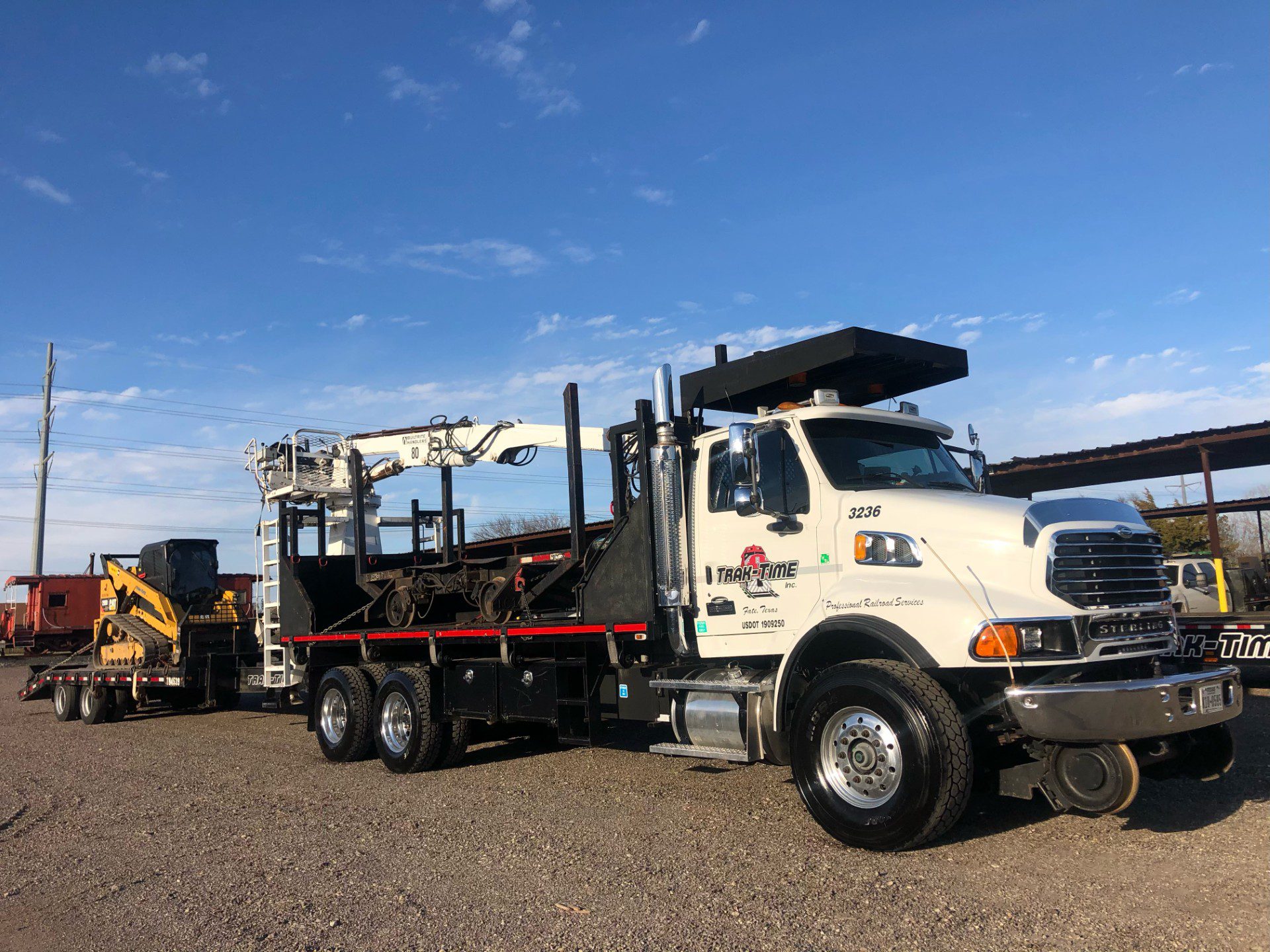 A large white truck equipped with drilling equipment under a clear blue sky.