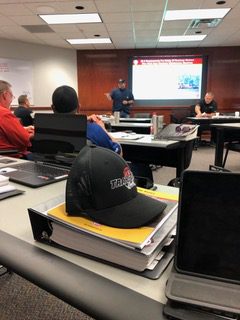 A classroom setting with students and a presenter at the front.