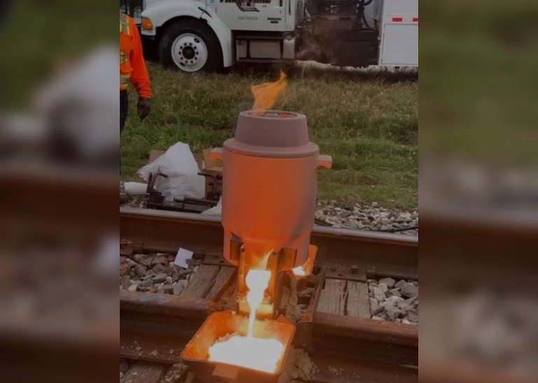 Molten metal flows from a crucible in an industrial setting.